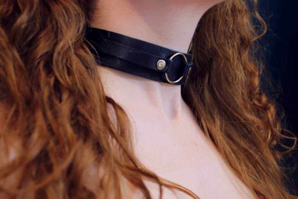 Submissive woman wearing black leather o-ring house collar